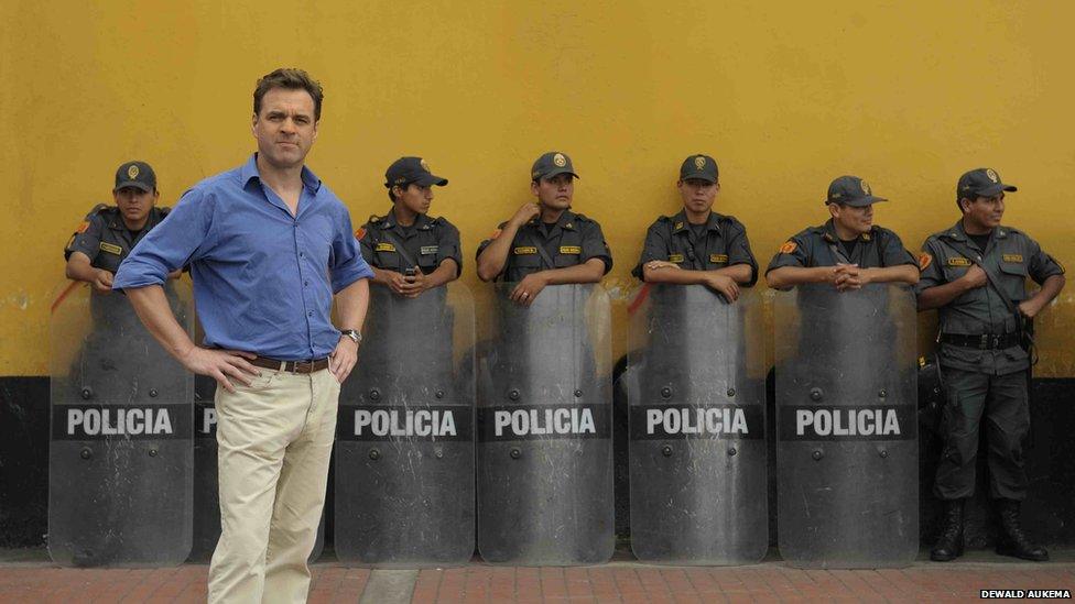 Prof Niall Ferguson stands in front of a row of policemen