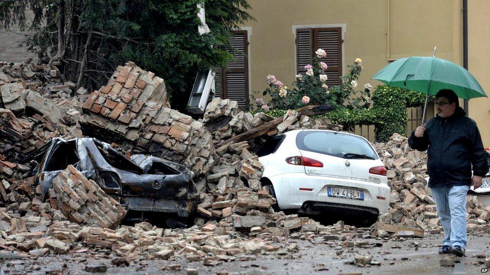 Cars lie crushed beneath rubble.