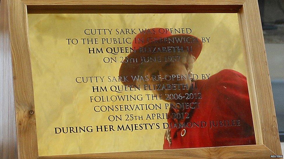 The Queen looks at her reflection in a commemorative plaque at the Cutty Sark.