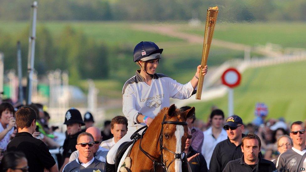 Zara Phillips carrying the Olympic flame on horseback at the end of day five at Cheltenham Racecourse.