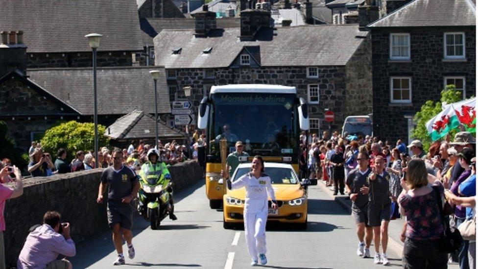 Sian Harries, sydd wedi gwella ar ôl torri ei chefn, yn cario'r Fflam dros y bont yn nhref Dolgellau wrth i'r Fflam anelu am Fangor