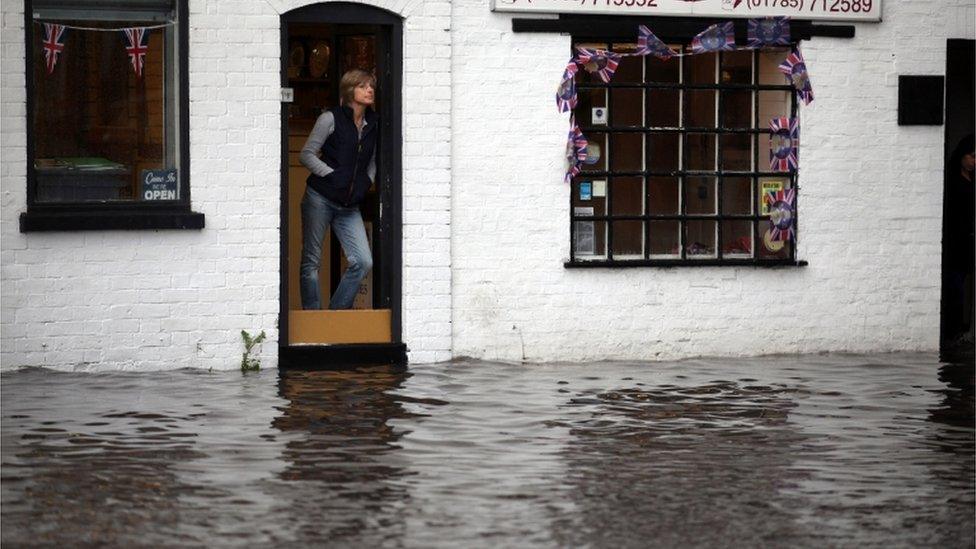 Shop workers look out at flash flooding in the Staffordshire village of Penkridge