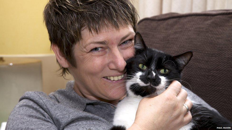 Woman cuddles black and white cat