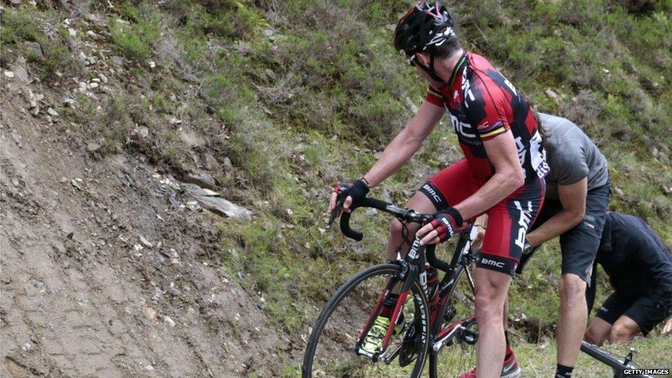 Tour de France 2011 winner Cadel Evans looks at a team member fixing a flat tyre caused by a member of the public who sprayed nails on the ground in the 191 km and fourteenth stage of the 2012 Tour de France.