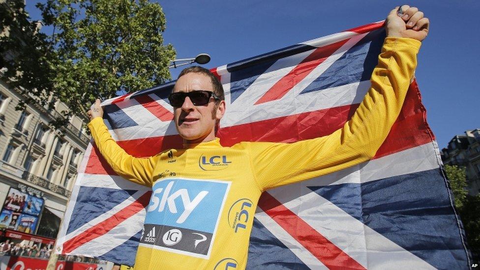 Bradley Wiggins, winner of the 2012 Tour de France cycling race holds the Union flag aloft during a parade after the last stage of the race in Paris, France.