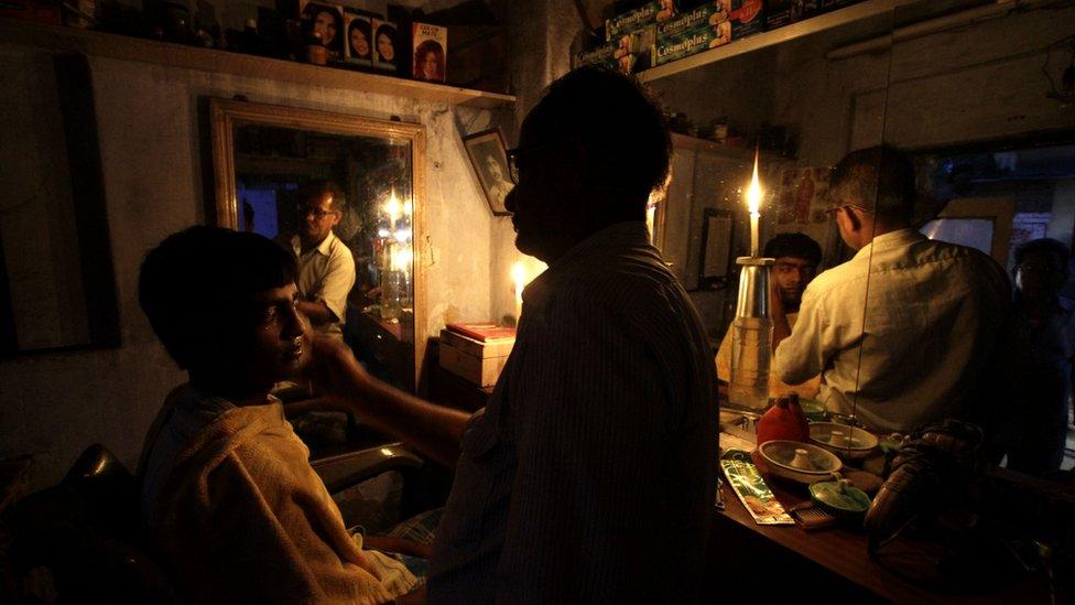 A man has a haircut by candle light in Calcutta, India (31 July 2012)