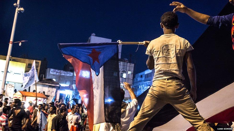 A Yemeni teenager holds a flag used by the Southern Movement during a march in Aden. Photo: Luke Somers