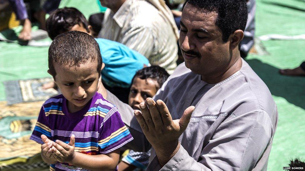 A father and son pray together during the Friday prayer in Mualla district, where the port of Aden is located. Photo: Luke Somers