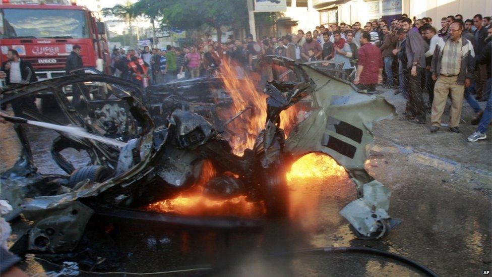 Crowds surround the burning wreckage of Ahmed Jabari's car.