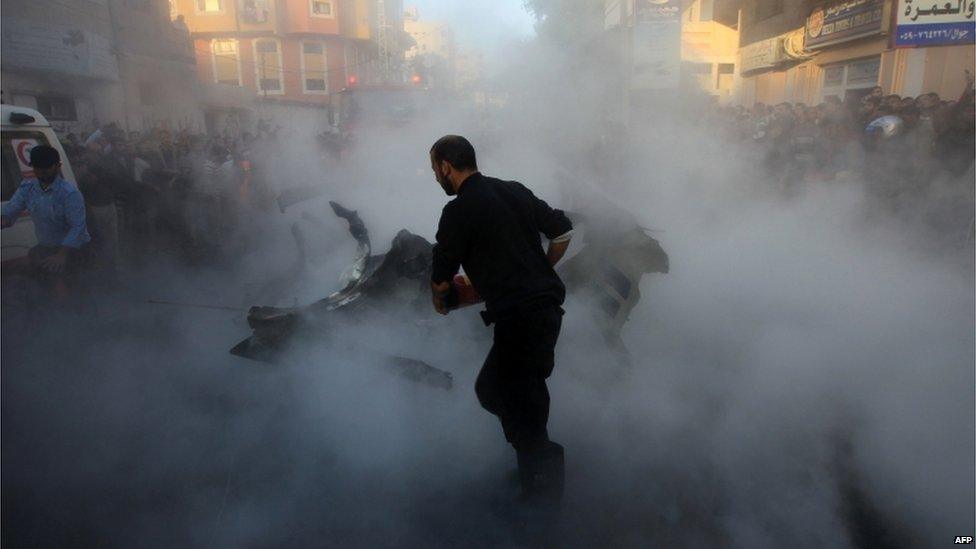 Palestinian firefighters extinguish the blaze on the burning wreckage.