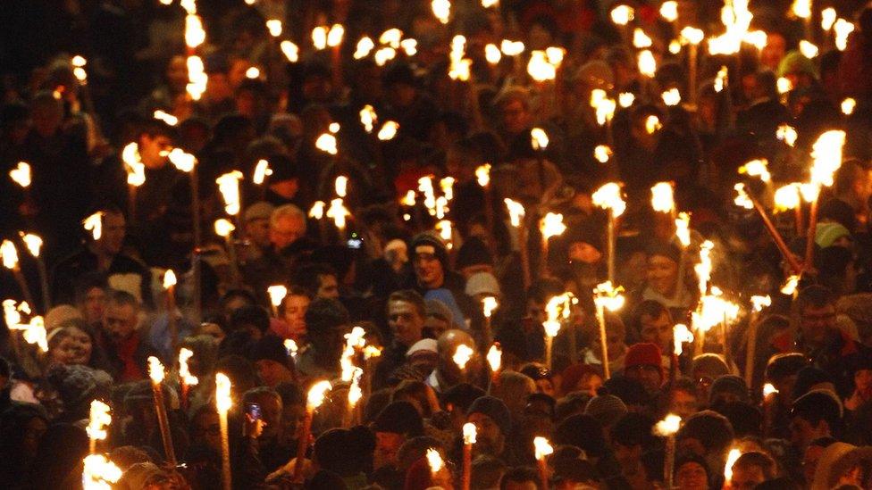 People walk down North Bridge carrying lit torches during the annual torchlight procession to mark the start of Hogmanay