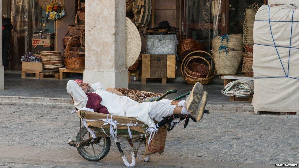 A market porter takes a nap during the mid-day break in the wheel barrow he uses to ferry people's shopping about.