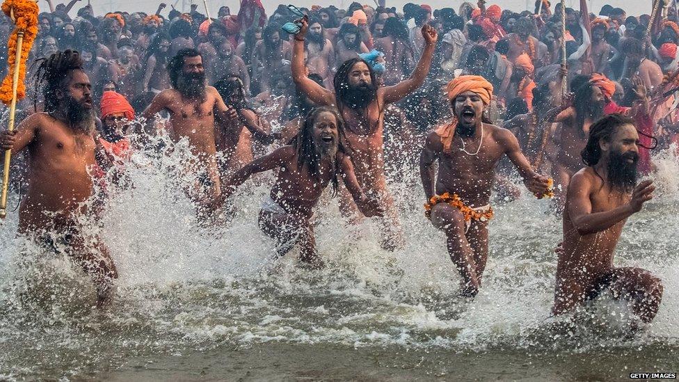 Naga sadhus run in to bathe in the waters of the holy Ganges river during the auspicious bathing day of Makar Sankranti of the Maha Kumbh Mela on 14 January 2013 in Allahabad, India