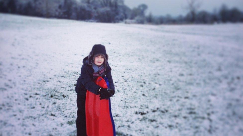 A boy stood on a snowy hill.