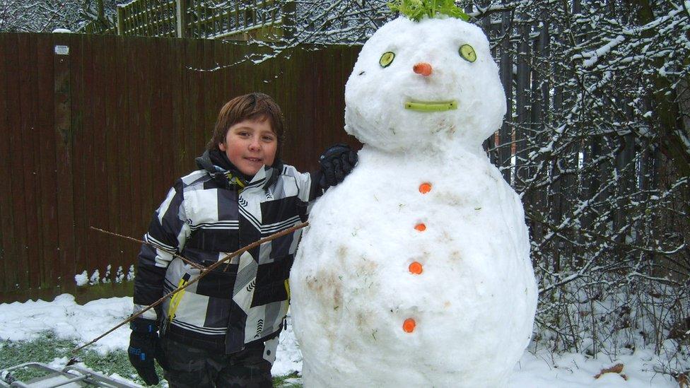 A snowman with vegetable features - a carrot nose and cucumber eyes.