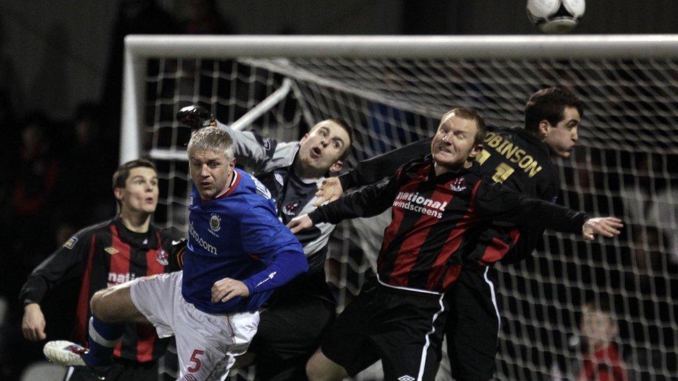 Crusaders debutant goalkeeper Craig Hyland clears from Linfield's William Murphy