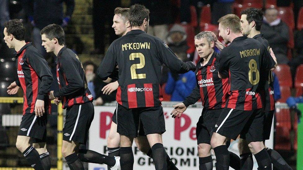 Crusaders players celebrate with Gary McCutcheon after his penalty kick levelled the score against Linfield at Seaview