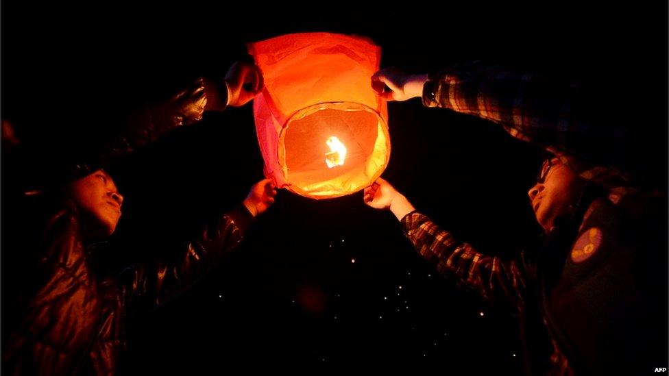 Chinese men release a paper lantern into the sky in Yuxian