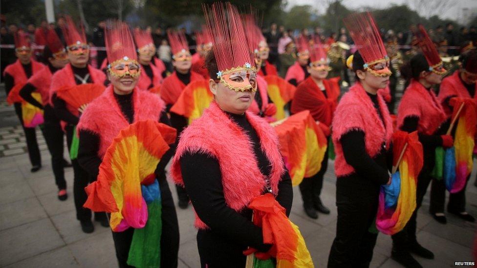 Masked dancers wait to perform on the outskirts of Wuhan in Heibei province