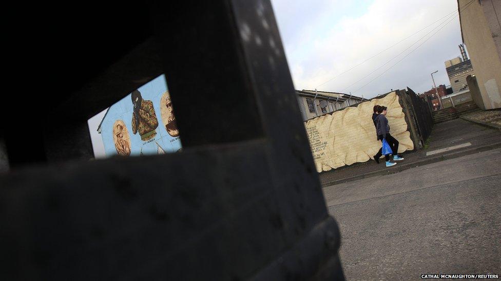 People walk past a loyalist paramilitary mural in the Shankill Road area of west Belfast