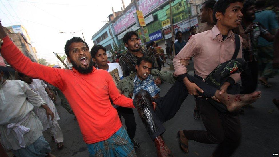 Activists carry a man injured in protests in Bogra, Bangladesh