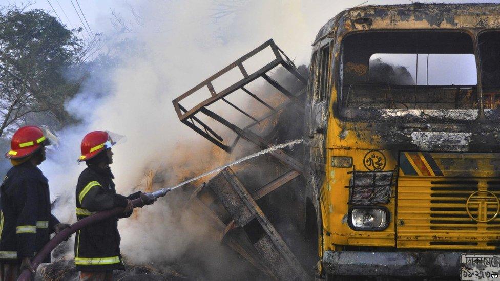 Fire-fighters try to douse flames of vehicle set alight by protesters, Rajshahi, Bangladesh