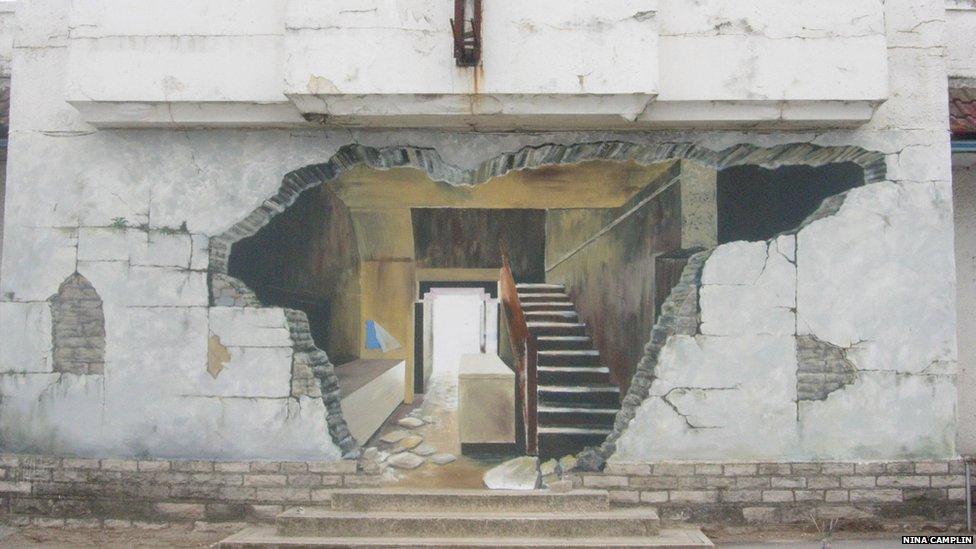 A mural that depicts a hole in a wall allowing the viewer to see into a house. Photo :Nina Camplin