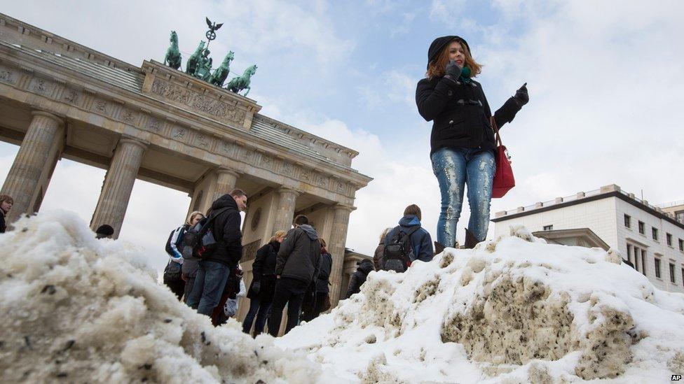 A tourist stands in front of the Brandenburg Gate in Berlin, Germany (12 March 2013)