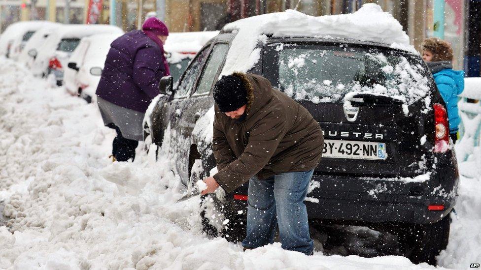 A family clear snow from their car in Cherbourg, France (12 March 2013)