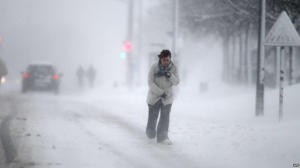 A woman walks through a blizzard in Caen, north-western France (12 March 2013)