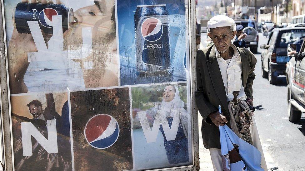 Old man on Sanaa street holds flag bearing the symbol – a rearing horse – of the General People’s Congress part