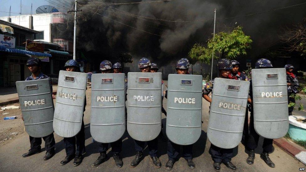 Policemen form a line as they block access to part of the town where a house is burning in riot-hit Meiktila, central Burma, on 22 March 2013