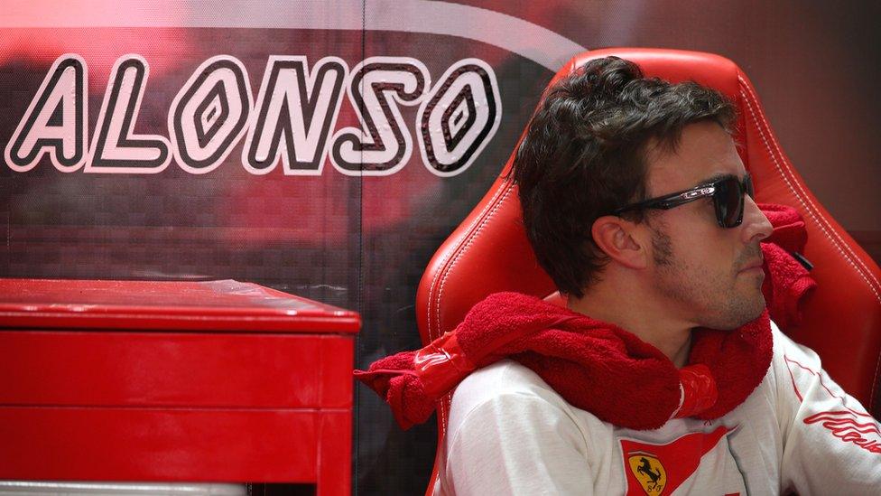 Ferrari's Fernando Alonso keeps dry while waiting for qualifying to start