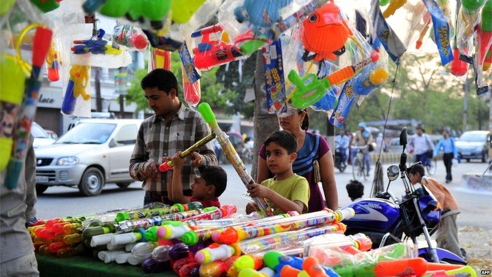 An Indian family purchase water guns from a roadside shop ahead of Holi festival in Allahabad on March 24, 2013