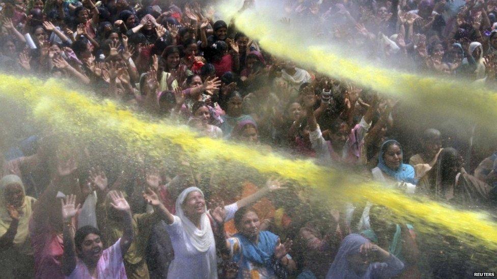 People raise their hands to receive coloured holy water from a priest during celebrations for Holi, also known as the festival of colours, in Jammu March 24, 2013.