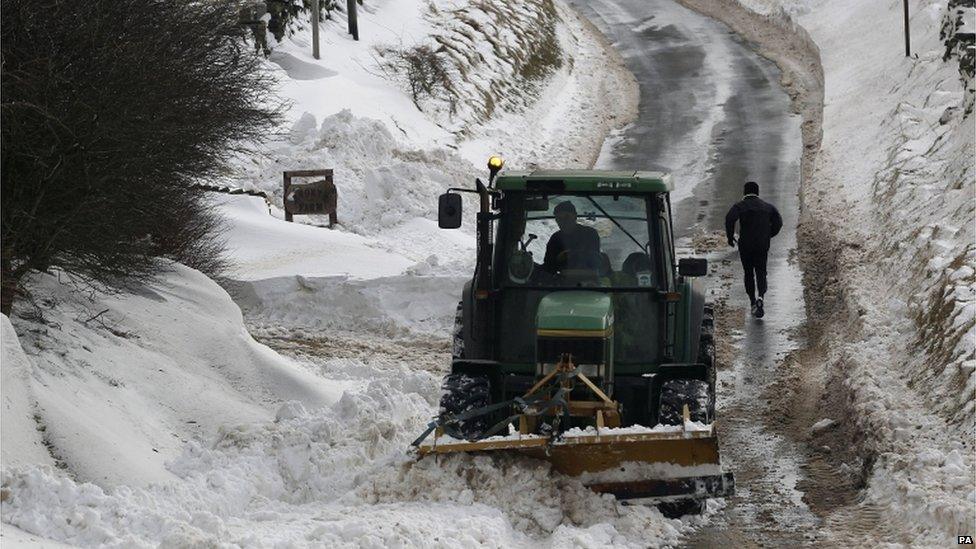 A runner makes his way up a cleared road flanked by deep snow in Burnley, Lancashire, on 25 March 2013