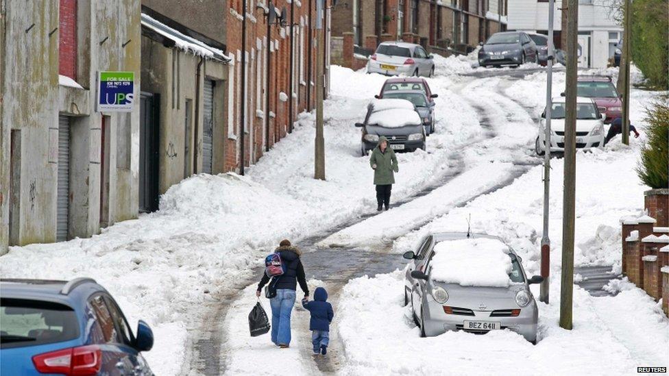 People walk through heavy snow as wintry weather continues to cause havoc across the United Kingdom, in north Belfast, on 25 March 2013