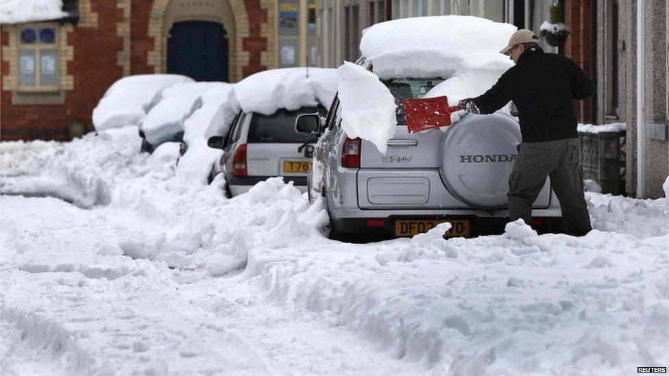 A man uses a shovel to clear snow from his car in Llangollen, north Wales, on 25 March 2013