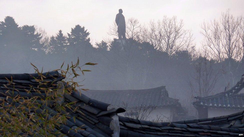 A large statue of Kim Il-Sung dominates the skyline at sunset over Kaesong, April 2011