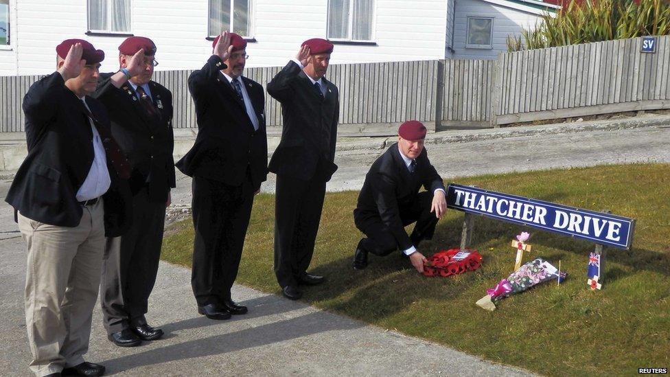 A group of former British paratroopers, who fought in the Falklands War, salute as they leave a wreath for former British prime minister Margaret Thatcher at a street sign in her name.