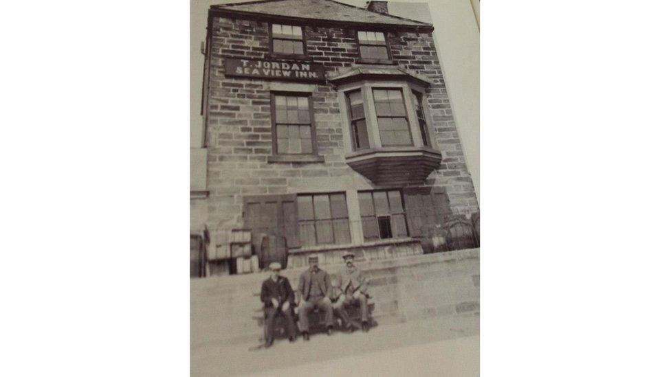 Three men sitting outside an inn