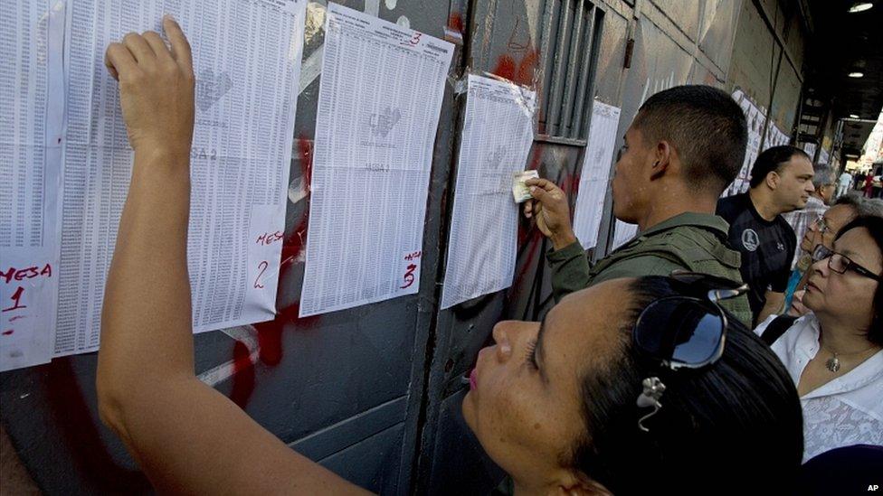 Caracas residents look for their names on the voters' list outside a polling station for voting in presidential elections