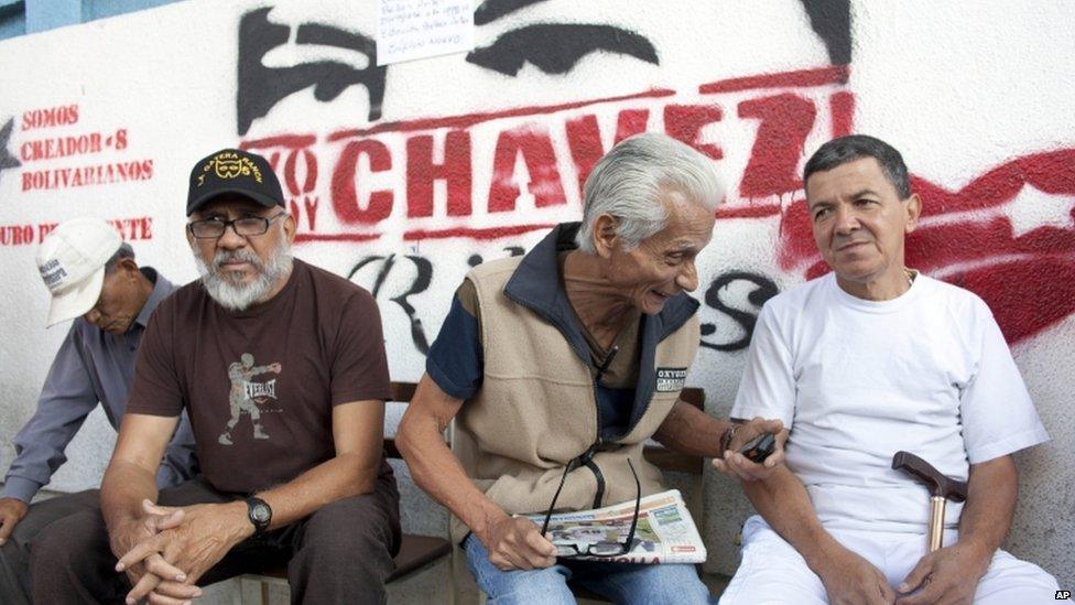 Residents sit as they queue to vote in the presidential election in Caracas