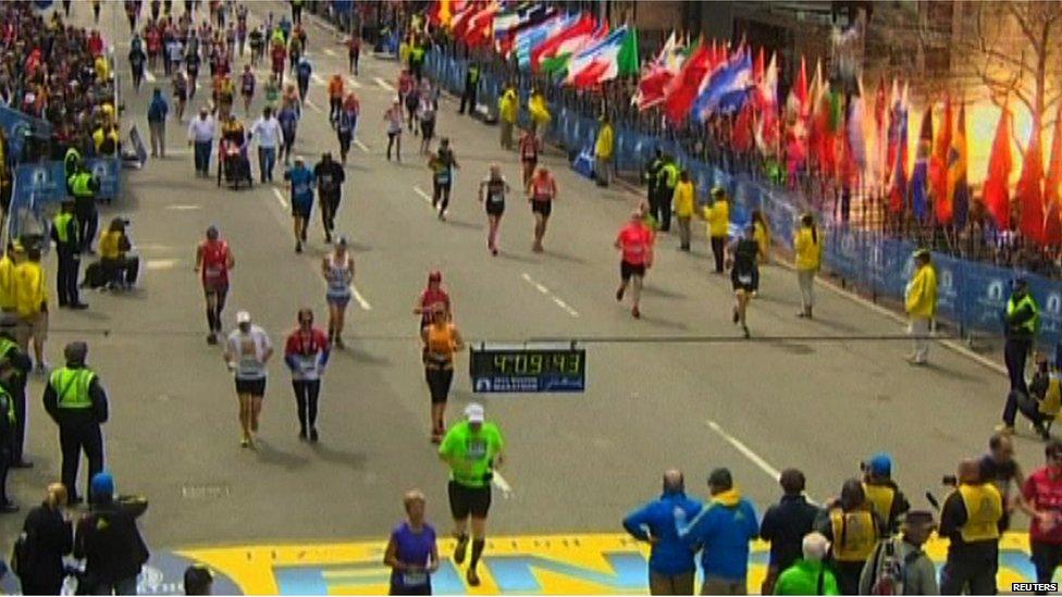 Competitors run as the first explosion is seen near the finish line of the marathon, Boston, 15 April 2013