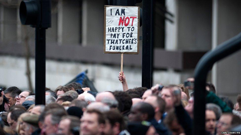 A member of the crowd holds up a sign