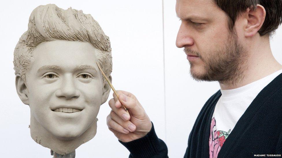 A sculptor works on the clay head of Niall Horan of One Direction.