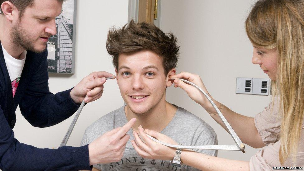 Louis Tomlinson of One Direction poses with calipers during a figure sitting where he is measured for a wax figure creation.