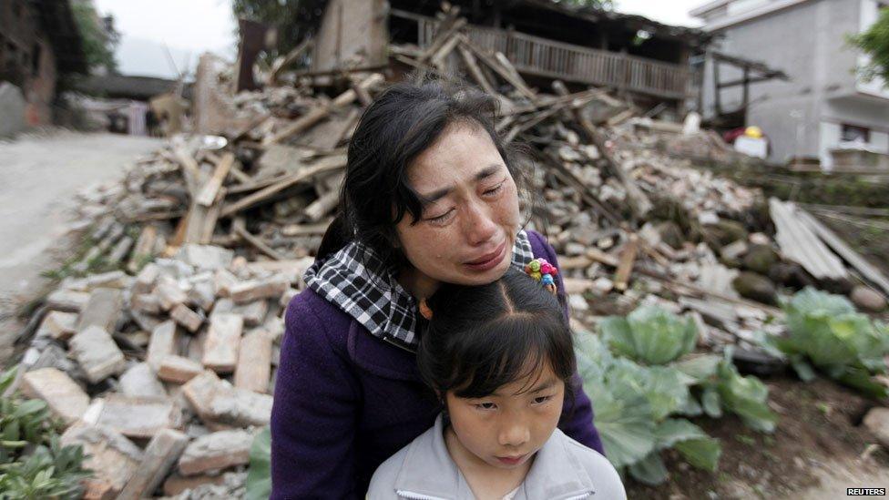 Song Zhengqiong, holding her daughter, cries in front of her damaged house after a strong 6.6 magnitude earthquake at Longmen village, Lushan county