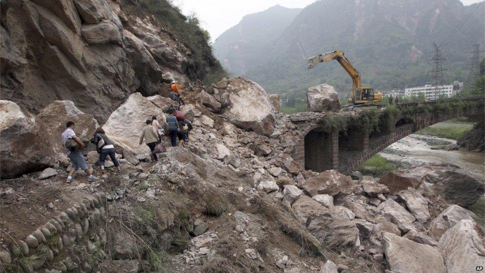 People walk along a damaged road in Baosheng, Lushan, Sichuan province, China (21 April 2013)