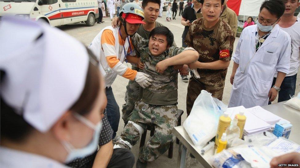 Medical officials treat a patient outside a hospital in Lushan County, Ya'an City, China (21 April 2013)